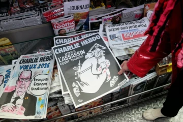 Une femme regarde dans un kiosque, le 6 janvier 2016 à Paris, le numéro spécial de Charlie Hebdo  paru un an après l'attentat
