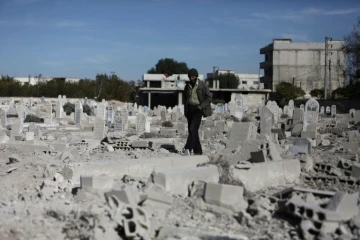 Un homme marche dans un cimetière détruit après des raids aériens dans le village de Deir al-Asafir dans la Goutha orientale, près de Damas, le 25 novembre 2015 