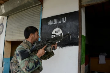 Un soldat de l'armée afghane pointe son arme sur un drapeau du groupe Etat islamique peint sur un mur à Kot, dans l'est de l'Afghanistan, le 26 juillet 2016