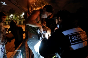Un officier de sécurité contrôle les sacs des "teufeurs" qui viennent participer à la free party au  bois de Vincennes, le 1er août 2020