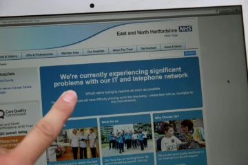 Une femme montre le site Web du NHS (East and North Hertfordshire), informant les utilisateurs d'un problème dans son réseau, à Londres le 12 mai 2017