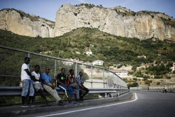 Des migrants attendent au bord d'une route dans la vallée de la Roya, près de Vintimille à la frontière franco-italienne, le 8 août 2017