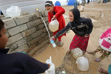 Des enfants remplissent d'eau des jerricans dans le camp de Hammam al-Alil, le 18 mars 2017 en Irak