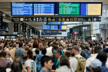 Des passagers autour des panneaux de départ et d'arrivée à la gare Montparnasse à Paris le 26 juillet 2024