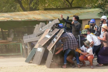 Des manifestants à couvert derrière des boucliers lors de heurts avec la police, le 7 mars 2021 à Nyaung-U, en Birmanie