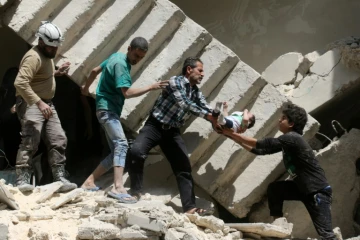 Des volontaires de la Défense civile syrienne, sortent un enfant des décombres d'un immeuble bombardé à Alep le 28 avril 2016