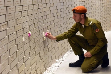 Un soldat israélien place une fleur sur les noms des soldats tués au service de leur pays ou dans des attentats, à Jérusalem, à l'occasion du Jour du Souvenir, le 18 avril 2018 
