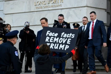 Une manifestante en faveur de la destitution de Donald Trump tient une pancarte à la sortie du  lieutenant-colonel Alexander Vindman, témoin dans l'enquête visant le président américain, le 19 novembre 2019