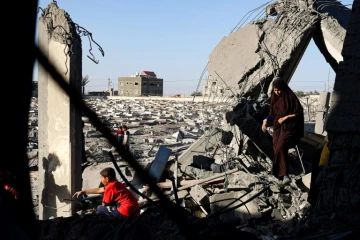 Une femme et des enfants palestiniens dans les décombres d'une maison touchée par des bombardements israéliens nocturnes à Rafah, dans le sud de la bande de Gaza, le 20 avril 2024