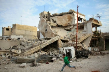 Un garçon syrien court devant un immeuble détruit par des raids du régime dans la ville de Douma, dans le fief rebelle de la Ghouta orientale, le 20 février 2018