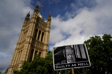 Une pancarte accuse le Premier ministre Boris Johnson d'être "aussi coupable que l'enfer" avant un vote de défiance, devant le Parlement à Londres le 6 juin 2022