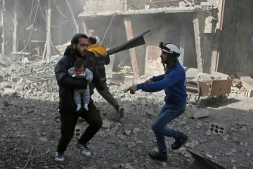 Un Syrien porte un bébé blessé dans la localité de Hamouria, dans l'enclave rebelle de la Ghouta orientale près de Damas, cible de violents bombardements du régime, le 19 février 2018 