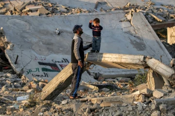 Des habitants de Gaza sur des décombres laissés par la guerre dans le camp de déplacés de Bureij, dans le centre du territoire palestinien, le 17 janvier 2025