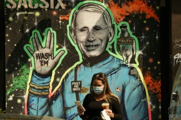 Des passants marchent devant une fresque représentant le Dr Anthony Fauci, directeur de l'Institut américain des maladies infectieuses, le 16 septembre 2020 à New York