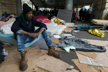 Un migrant assis sur un matelas dans un camp sous la station de métro Stalingrad à Paris le 24 mars 2016