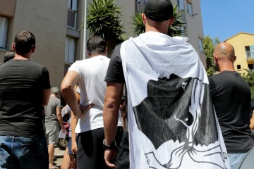 Un homme arbore un drapeau corse pendant une manifestation à la cité des Monts à Lupino, le 14 août 2016, après une rixe sur une plage à Sisco