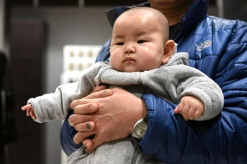 Un bébé chinois dans les bras de son père le 19 janvier 2015 à Pékin