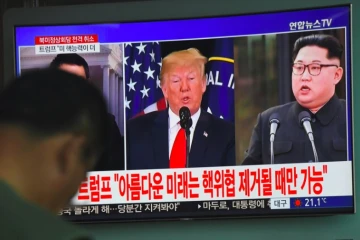 Les photos du président américain Donald Trump (g) et du leader nord-coréen Kim Jong Un sur un écran de télévision dans une gare de Séoul, le 25 mai 2018, après l'annulation du sommet entre les deux dirigeants
