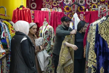 Le styliste Khourched Sattorov présente des vêtements traditionnels à des clientes dans son atelier à Douchanbé, le 2 décembre 2024 au Tadjikistan