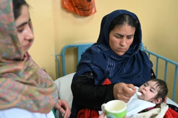 Samira (g), infirmière du service de malnutrition de l'hôpital de Baharak, donne du lait à la cuillère à une enfant, le 26 février 2024 dans la province du Badakhshan, en Afghanistan