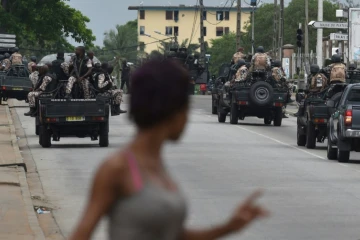 Une femme regarde les soldats ivoiriens qui patrouillent près du quartier général de l'armée, le camp militaire de Gallieni, à Abidjan le 12 mai 2017 