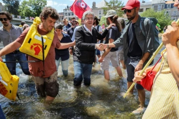 Le leader de la France insoumise (LFI) et chef de la coalition de gauche Nupes (Nouvelle allinace progressiste écologiste et sociale) Jean-Luc Melenchon (centre) serre la main de ses parisans alors qu'il traverse la rivière Clain près du pont de Joubert à Poitiers, sud-ouest de la France, le 2 juin 2022

