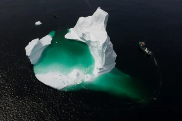 Un bateau contourne un iceberg dans les eaux du Canada en 2019