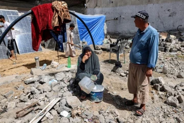 Une femme est assise avec des conteneurs vides, le 5 avril 2024 à Rafah, dans le sud de Gaza