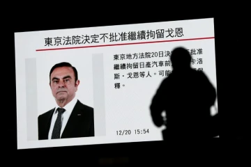 Un piéton passe devant un écran sur lequel est diffusé un programme sur l'ex PDG de Renault et de l'Alliance Renault-Nissan Carlos Ghosn, à Tokyo, le 20 décembre 2018 