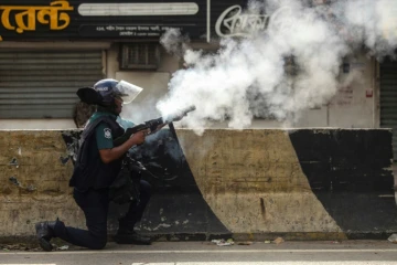 Un policier tire des gaz lacrymogènes, à Dacca, le 19 juillet 2024