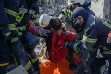 Des sauveteurs évacuent un soldat ukrainien sauvé après avoir été coincé 30 heures dans les débris d'une caserne militaire touchée par des roquettes russes, à Mykolaïv, dans le sud de l'Ukraine, le 19 mars 2022


