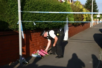 Un policier dépose des fleurs, le 29 juillet 2024, en hommage aux victimes d'une attaque au couteau qui a fait deux morts et neuf blessés parmi des enfants participant à un atelier de danse à Southport, au nord-ouest de l'Angleterre.
