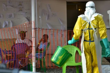 Un soigneur marche vers des patients en quarantaine dans un centre de traitement d'Ebola à Conakry, en Guinée, le 21 août 2015