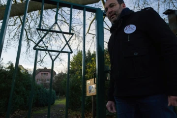Un volontaire des "veilleurs de mémoire", Lionel Godmet, devant la porte du cimetière juif de Jungholtz, dans l'est de la France, le 10 décembre 2019