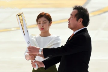 Le Premier ministre sud-coréen Lee Nak-Yon (d) et la médaille d'or du patinage artistique Kim Yu-Na portent la flamme olympique, le 1er novembre 2017 à l'aéroport de Séoul lors d'une cérémonie pour son arrivée en Corée du Sud