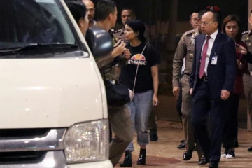 La jeune Saoudienne Rahaf Mohammed al-Qanun (C) est escortée vers un véhicule par un responsable thaïlandais de l'immigration et des délégués du Haut commissariat aux réfugiés de l'ONU, à l'aéroport Suvarnabhumi de Bangkok, le 7 janvier 2019