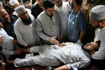 Le gouverneur de la province de Khyber Pakhtunkhwa, Haji Ghulam Ali (centre), réconforte un homme blessé lors de l'attentat suicide contre un meeting politique, le 30 juillet 2023 dans un hôpital de Peshawar (Pakistan)