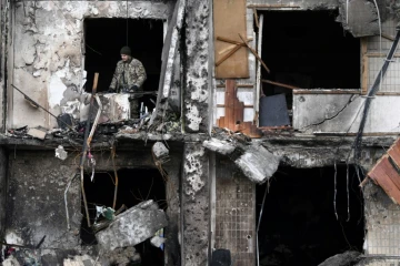 Un soldat ukrainien consate les dégâts dans un immeuble endommagé par des tirs russes à Kiev, le 26 février 2022