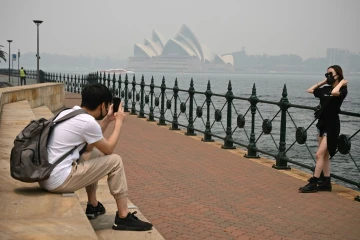 Des touristes portent des masques en raison des fumées toxiques liées aux incendies de forêts, le 10 décembre 2019 à Sydney, en Australie