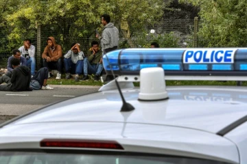 Une voiture de police et des migrants près du port de Calais, le 16 août 2017