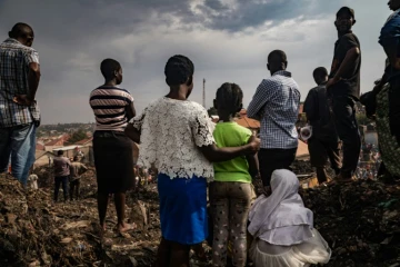 Des habitants assistent aux recherches des secours après l'effondrement d'une décharge à Kampala, le 10 août 2024 