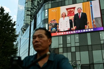Un homme passe à Pékin devant un écran montrant la rencontre entre la cheffe du gouvernement italien Giorgia Meloni et le président chinois Xi Jinping le 28 juillet 2024