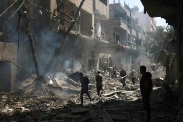 Des Palestiniens marchent le 8 juin 2024 dans des gravats de bâtiments détruits lors d'une opération israélienne pour libérer des otages à Nousseirat, dans le centre de la bande de Gaza, où une guerre oppose Israël au mouvement islamiste Hamas