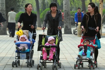 Des femmes avec des enfants en poussette à travers un parc de Pékin, le 5 avril 2011