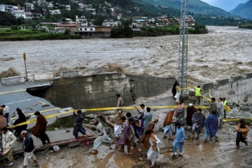 Des personnes se rassemblent devant une route endommagée par inondations consécutives aux fortes pluies de mousson dans la vallée de Swat, dans le nord du Pakistan, le 27 août 2022