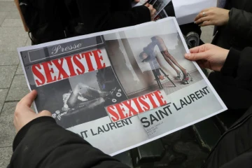 Une personne montre deux reproductions des affiches Saint Laurent, lors d'une manifestation à Paris le 7 mars 2017. Jugées "dégradantes" pour l'image de la femme, ces images ont finalement été retirées
