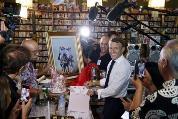 Le président français Emmanuel Macron reçoit un cadeau de la part de Boualem Benhaoua, patron du label de raï Disco Maghreb à Oran, le 27 août 2022