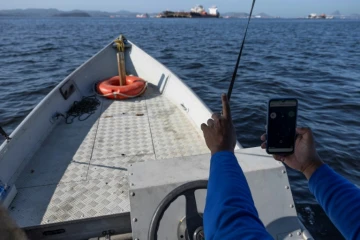 Alexandre Anderson de Souza, président de l'association de pêcheurs Ahomar, utilise une application pour dénoncer des délits environnementaux, le 1er août 2024, à Rio de Janeiro