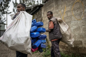 Dereje Enigdamekonen (d) et Ezedin Muste, deux collecteurs "korales" de déchets, parcourent un quartier proche de Merkato à la recherche de plastique, le 1er octobre 2024 à Addis-Abeba, en Ethiopie