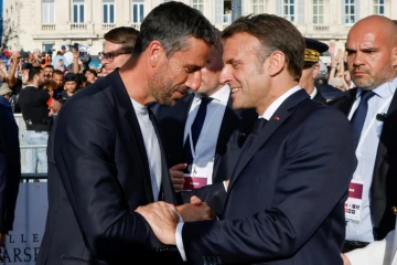 Le patron du comité d'organisation de Paris 2024 Tony Estanguet (G) serre la main du président  Emmanuel Macron à l'arrivée de la flamme olympique à Marseille le 8 mai 2024